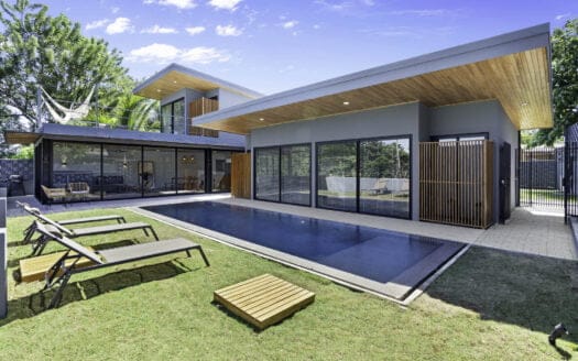 A luxurious modern home in Tamarindo featuring a stunning pool and elegant lounge chairs for relaxation.