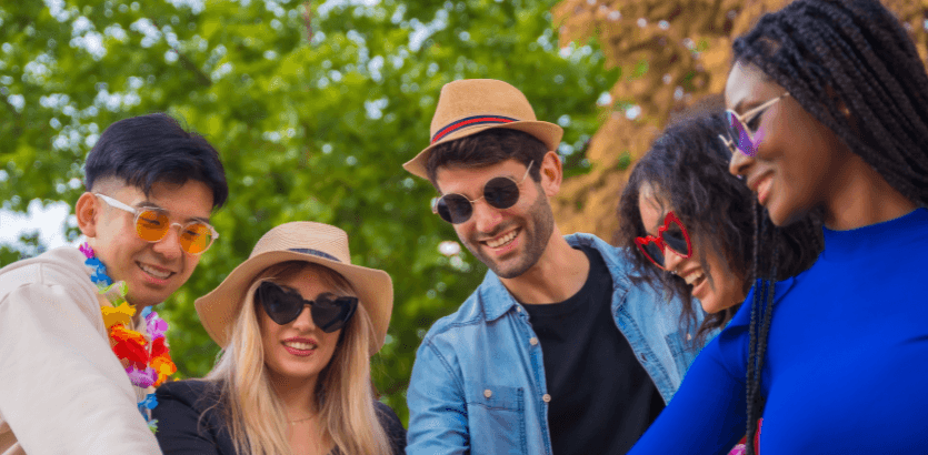 A diverse group of individuals wearing sunglasses and hats, enjoying a sunny day outdoors.