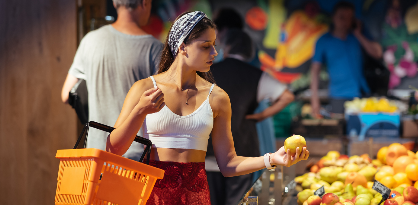 A woman stands holding a basket filled with a variety of fresh fruits, showcasing vibrant colors and textures.