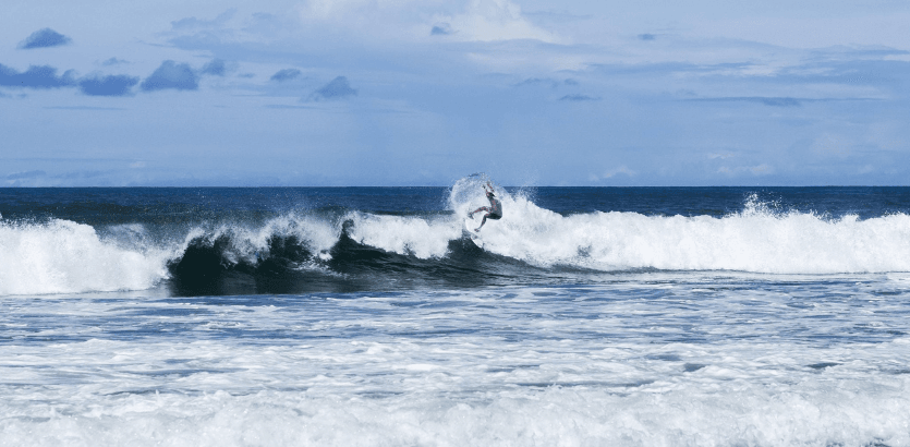 A surfer skillfully rides a wave on a surfboard, showcasing balance and agility in the ocean's dynamic environment.