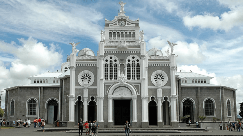 A large white church featuring a prominent tower, set against a clear blue sky, showcasing its architectural grandeur.