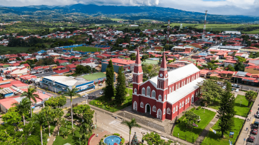 Aerial view of a picturesque mountain town, showcasing its charming buildings nestled among lush greenery and peaks.