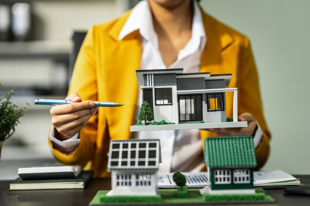 A businesswoman is reviewing contract papers at her desk in a sustainable house and condition.