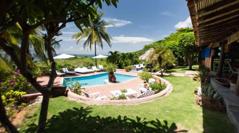 A serene tropical pool and lounge area surrounded by lush greenery and vibrant flowers, inviting relaxation and leisure.