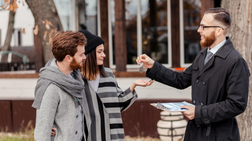 A man and woman engage in conversation with a real estate agent in a professional setting.