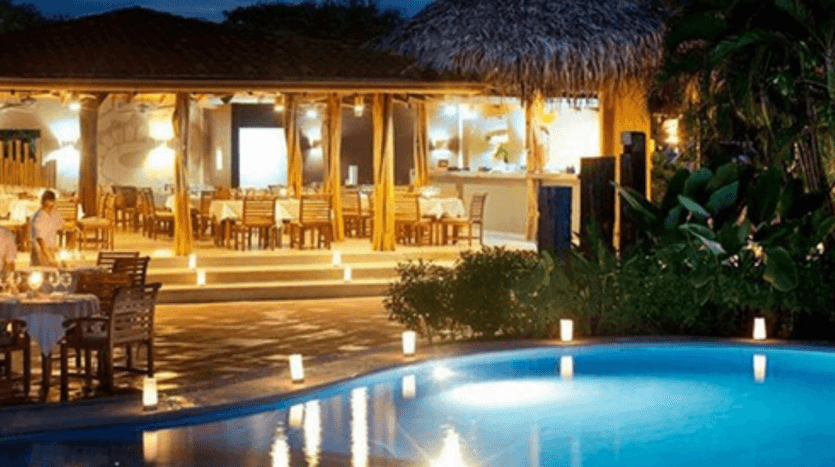A serene night scene featuring a pool illuminated by softly glowing candles, creating a tranquil atmosphere.