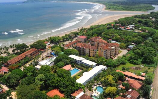 Aerial view showcasing a luxurious resort adjacent to a pristine beach, highlighting the vibrant blue waters and sandy shore.