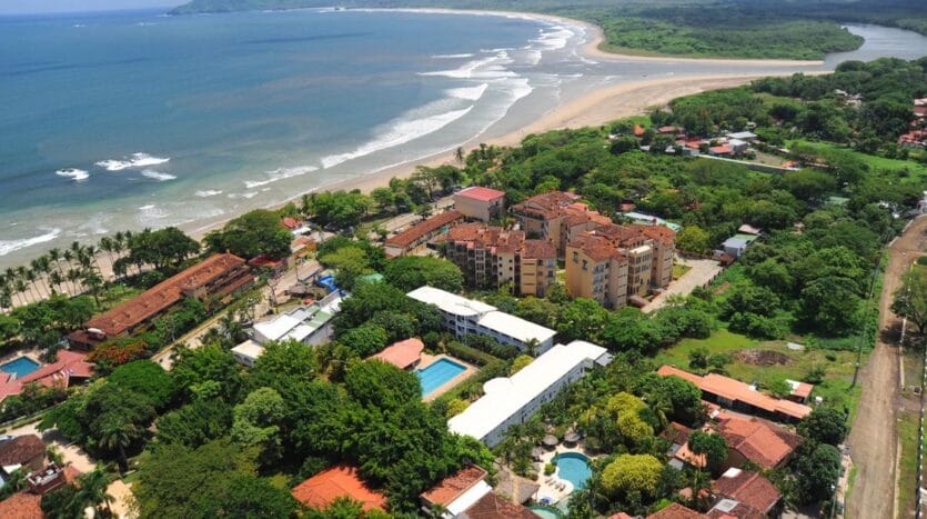 Aerial view showcasing a luxurious resort adjacent to a pristine beach, highlighting the vibrant blue waters and sandy shore.