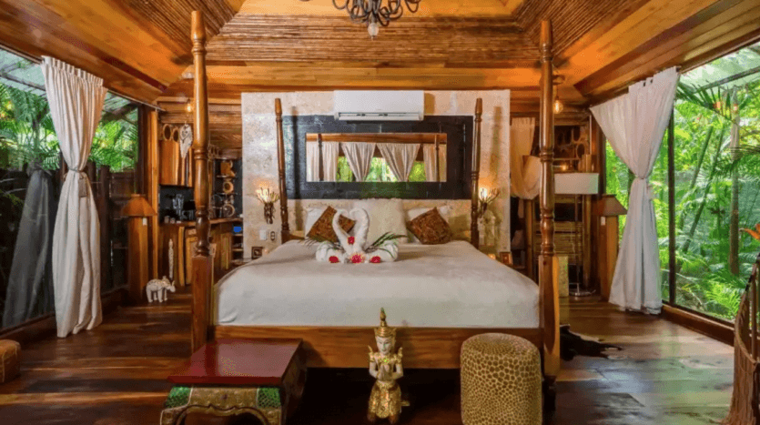 A serene bedroom featuring a canopy bed and a large window, allowing natural light to fill the space.